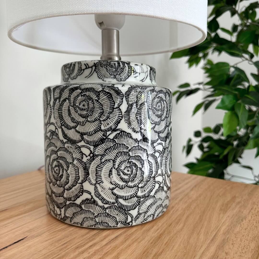 The stylish Camelia Table Lamp has a black and white ceramic base with a floral design and white fabric shade, 