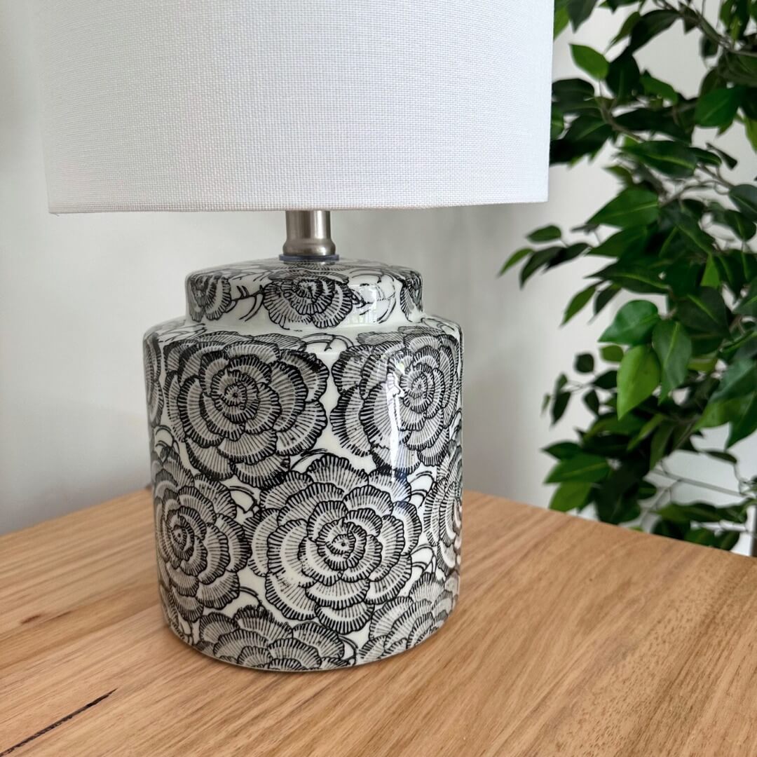 The beautiful Camelia Table Lamp has a black and white ceramic base with a floral design and white fabric shade, 