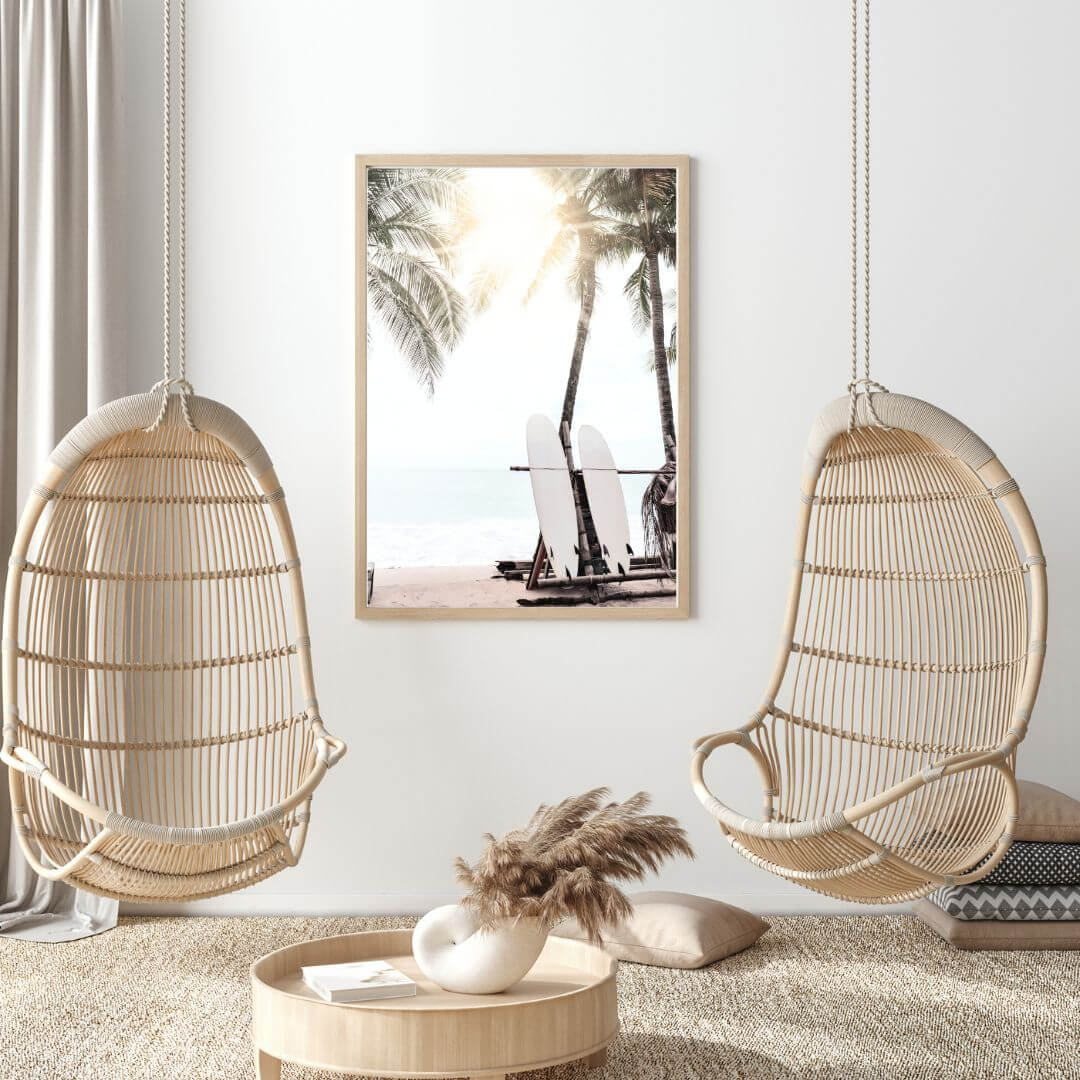 A relaxing coastal art print of two white surf boards under palm trees on a beach in Hawaii with the sun setting in the background. 