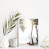 A wall art print on a shelf of two surf boards under the palm trees on a surfer beach in Hawaii framed in white