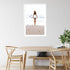 A wall art photo print of the girl with the surfboard with a white frame, white border on dining room wall