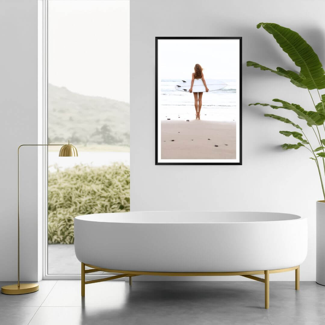 Decorate your empty walls with a wall art print of a girl holding a surfboard at the beach, available framed or unframed